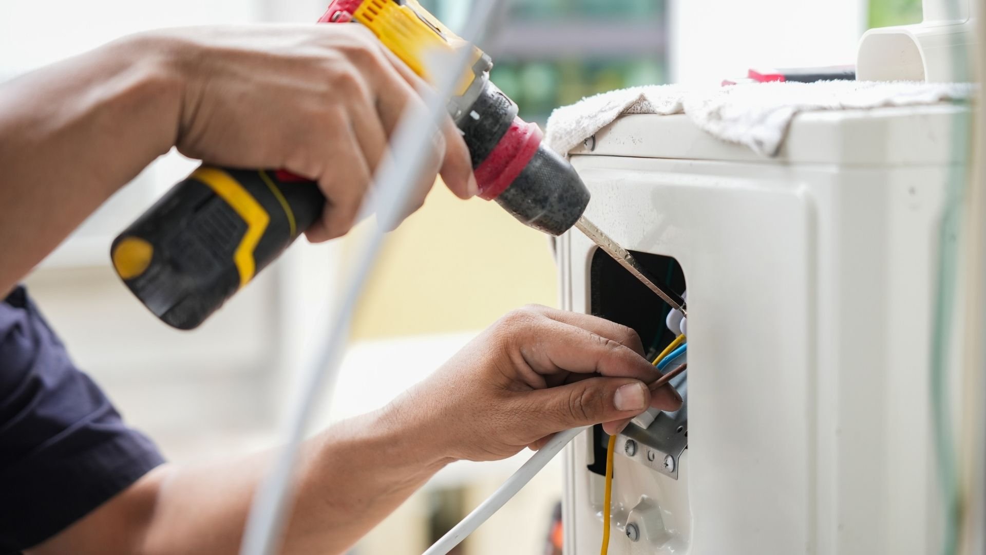 Electrician using screwdriver drill on electrical outlet wiring installation