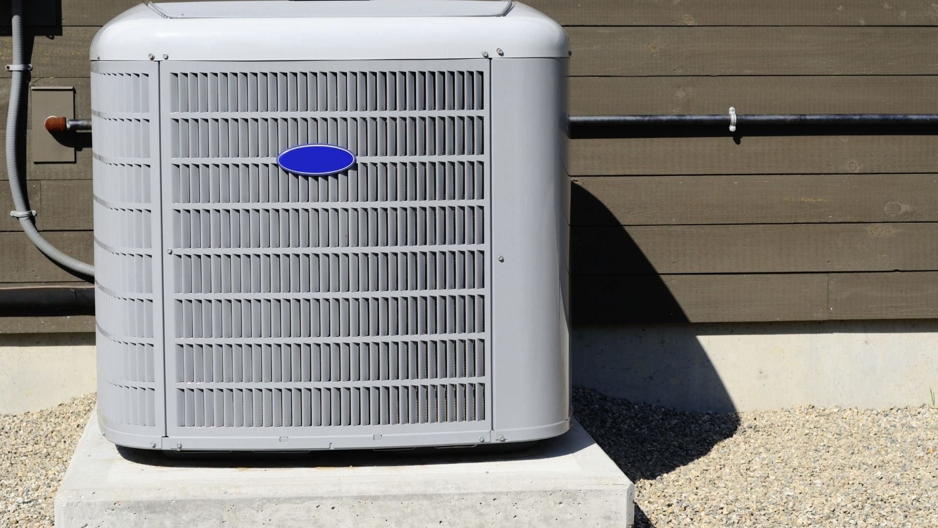 White air conditioning unit with blue oval logo on residential concrete pad