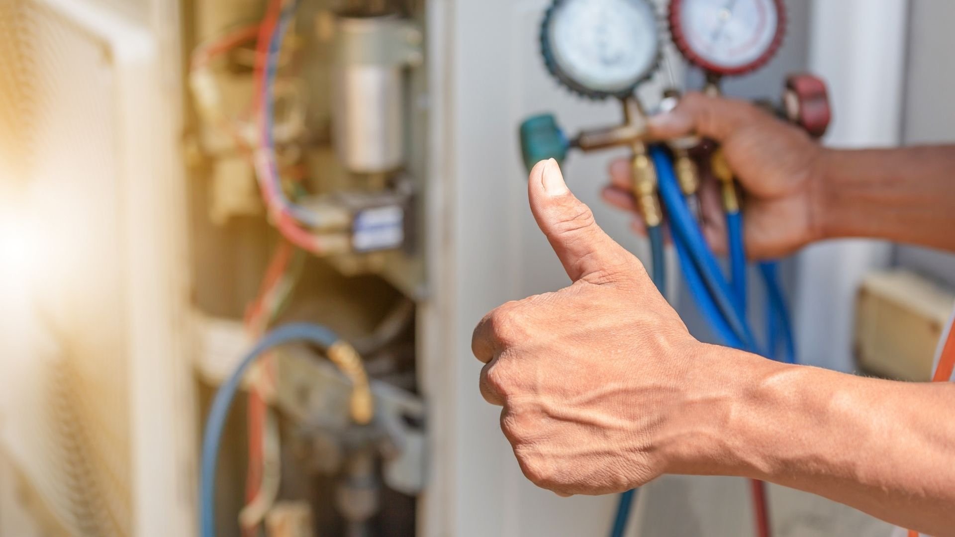 Technician giving thumbs up near HVAC equipment and pressure gauges