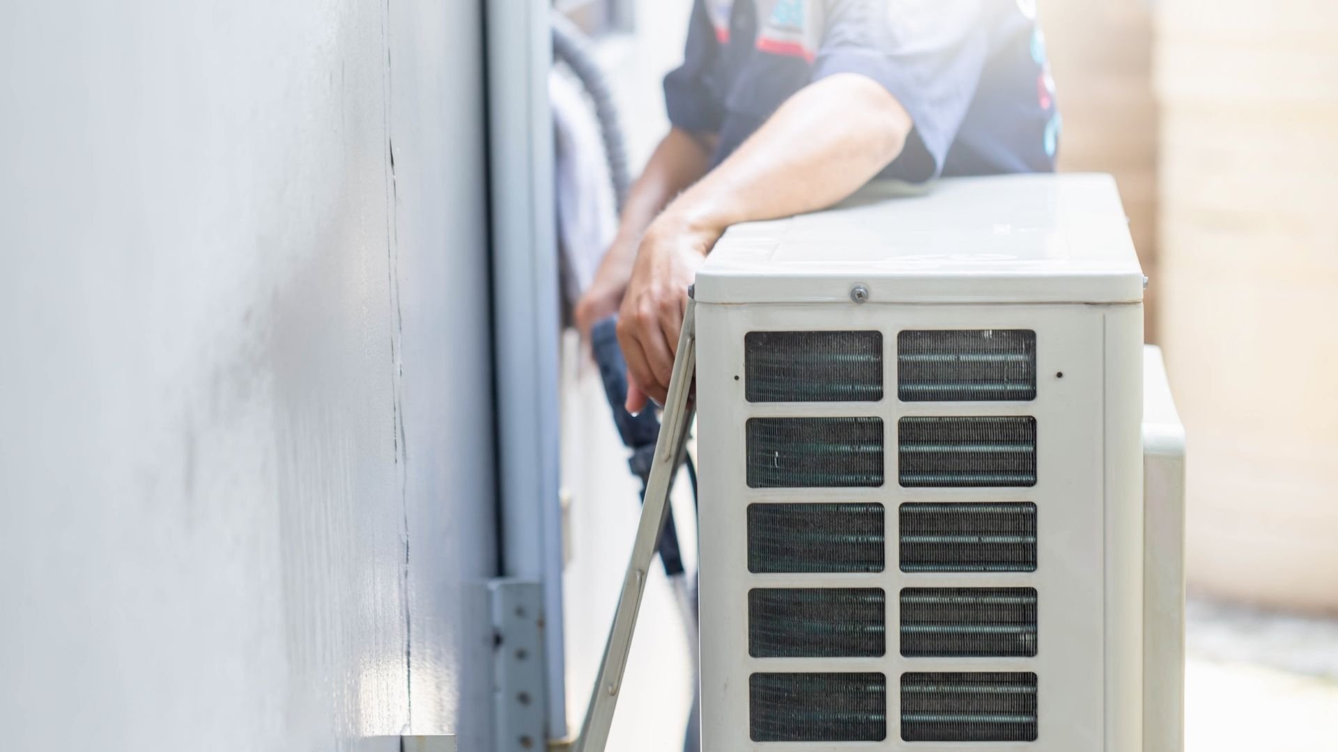 Technician installing or maintaining an outdoor air conditioning unit with multiple finned coils
