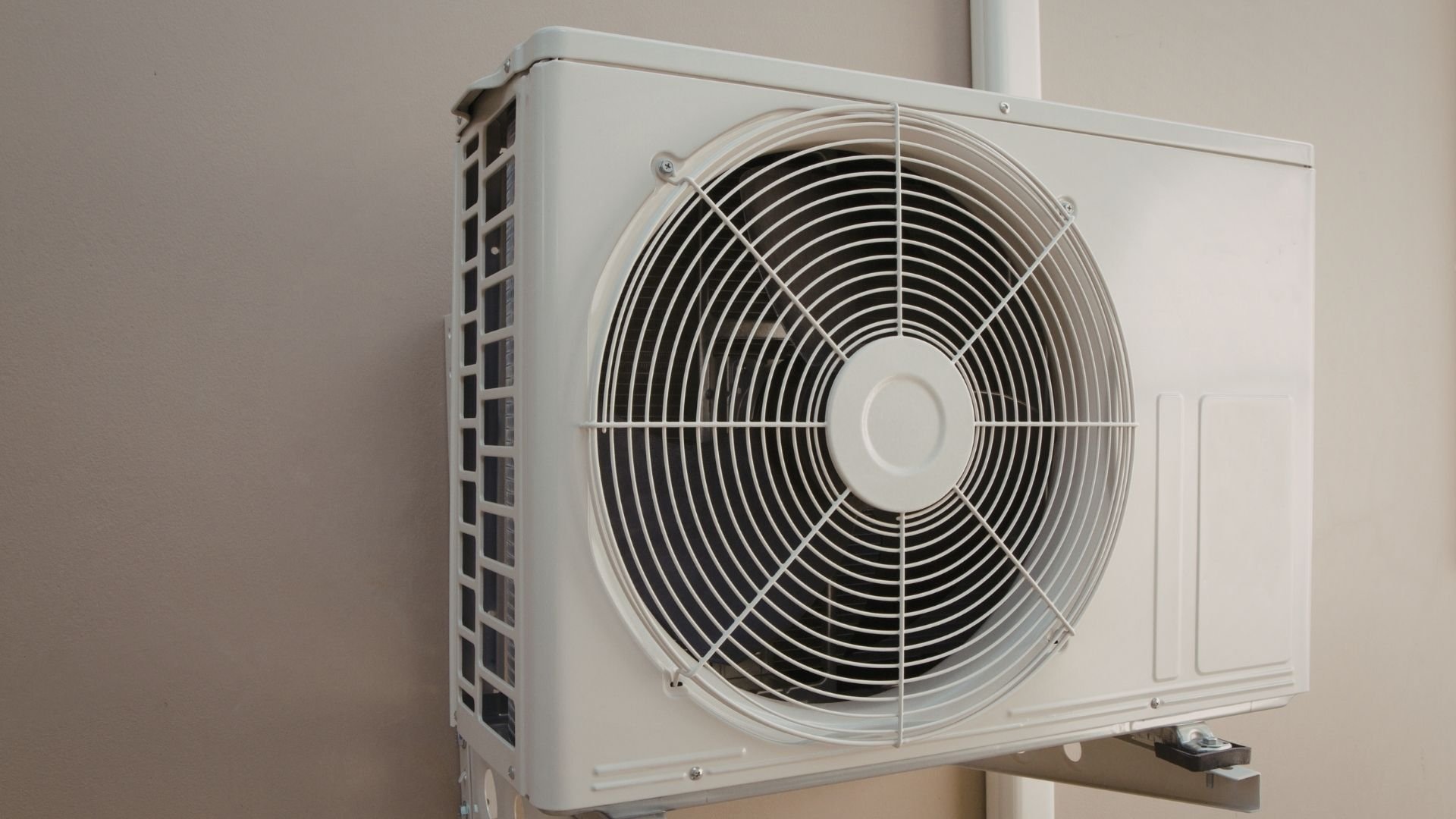 White outdoor air conditioning unit with large circular fan mounted on wall