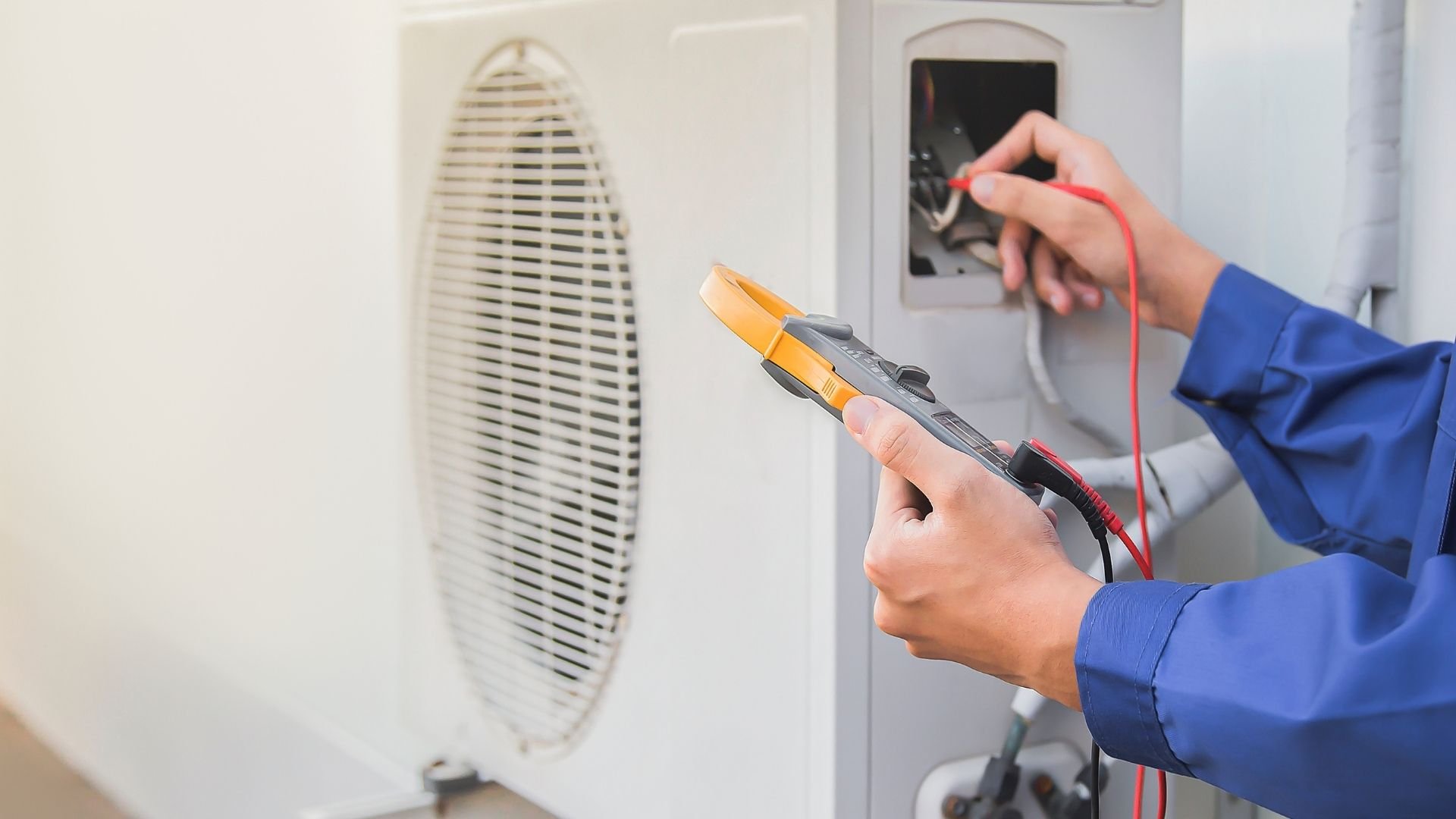 Electrician testing electrical outlet with multimeter in blue uniform.