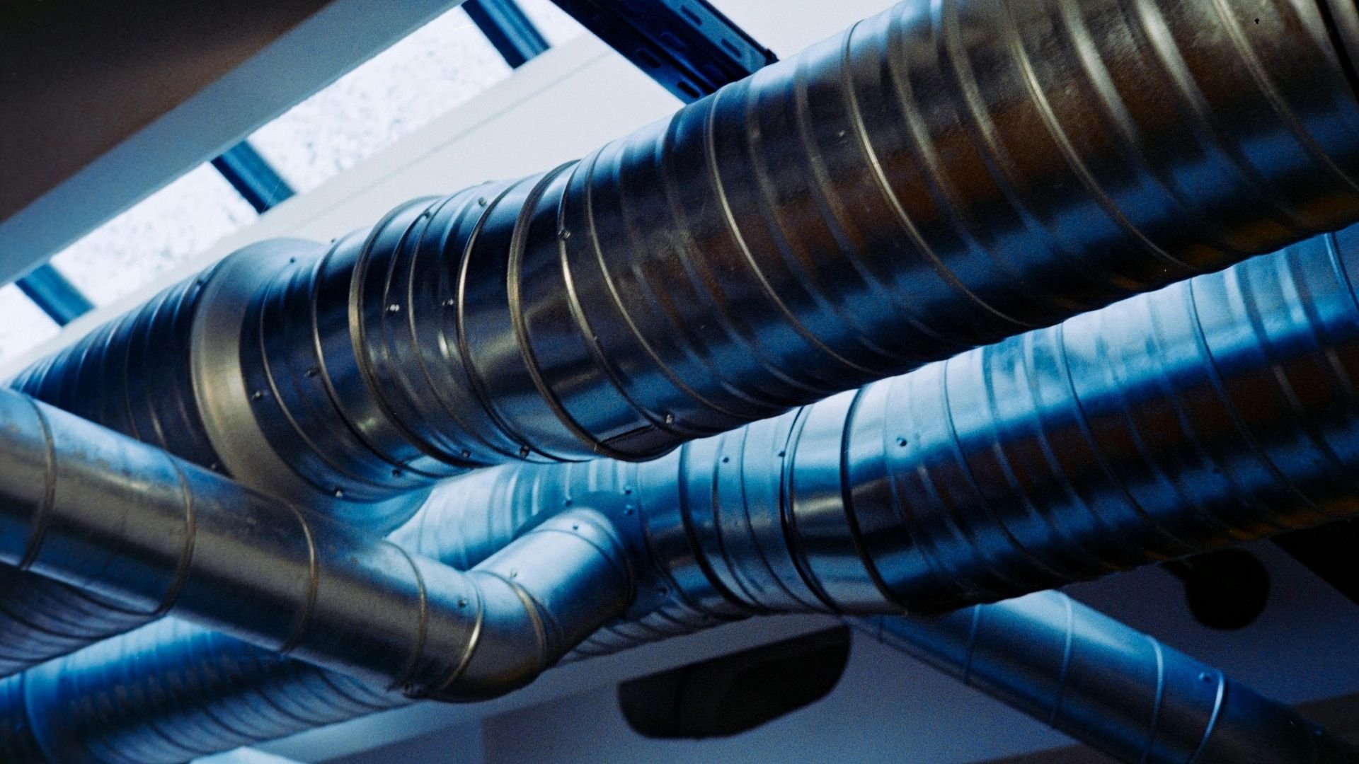 Industrial metal pipes with blue connectors and striped bands in technical infrastructure system